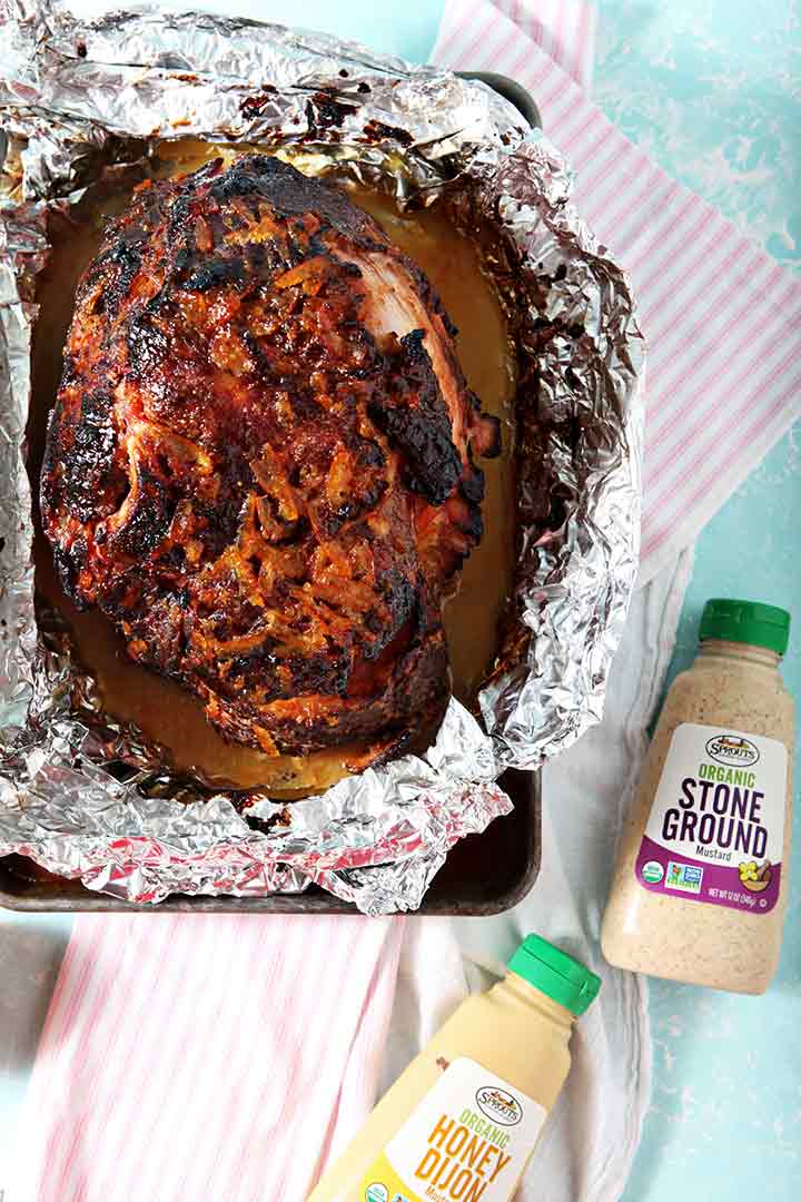 Ingredients for the glaze are shown beside a spiral ham after the glaze is brushed onto it