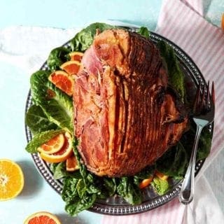 A Baked Ham with Bourbon Orange Glaze sits on a platter, ready for serving