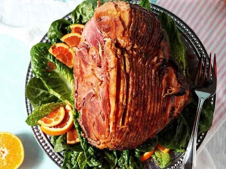 A Baked Ham with Bourbon Orange Glaze sits on a platter, ready for serving