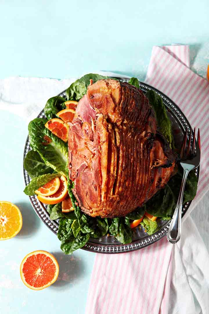 A Baked Ham with Bourbon Orange Glaze sits on a platter, ready for serving