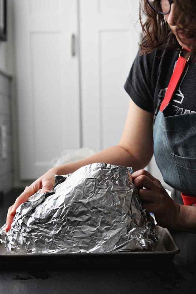 A woman wraps the spiral ham before baking in the oven