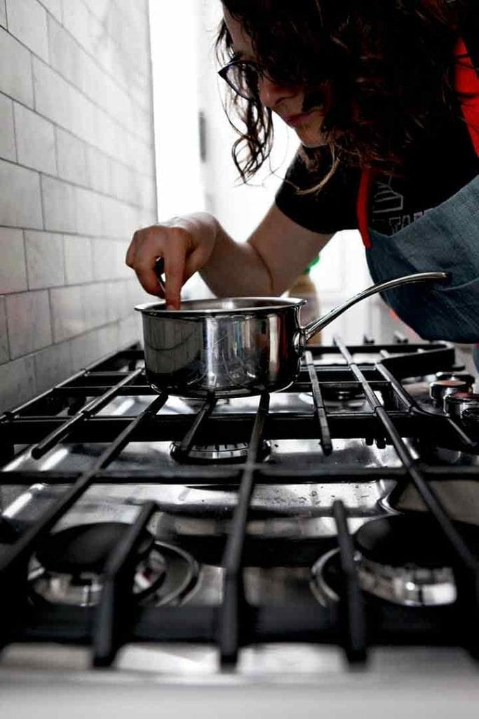 A woman stirs the bourbon orange glaze on the stovetop as it cooks down