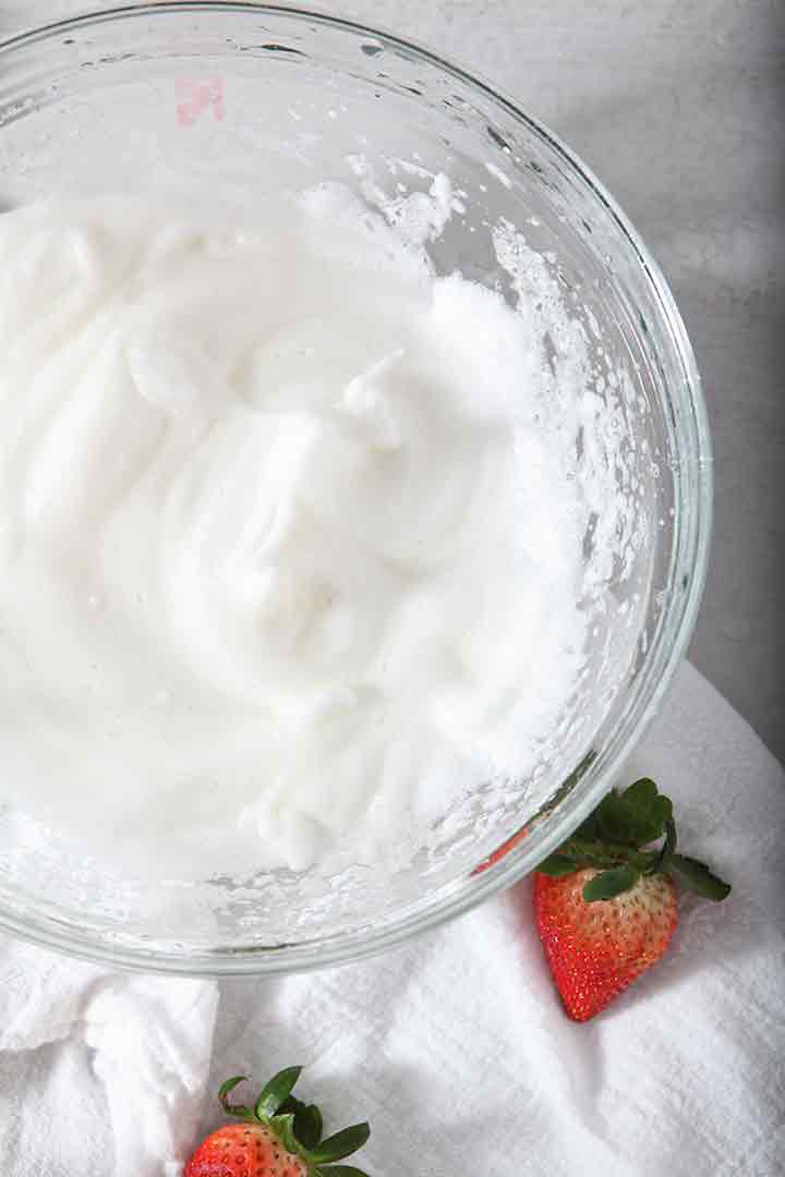 A bowl of whipped egg whites, made into soft peaks, are shown