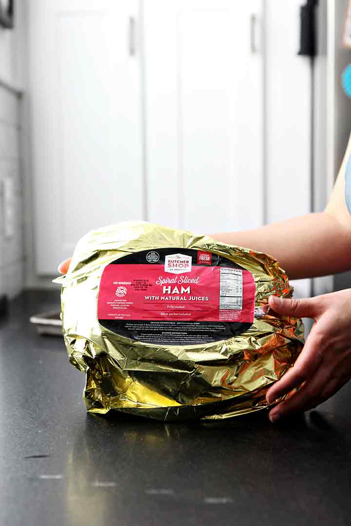 A Sprouts Bone-In Spiral Sliced Ham is opened on a countertop before baking