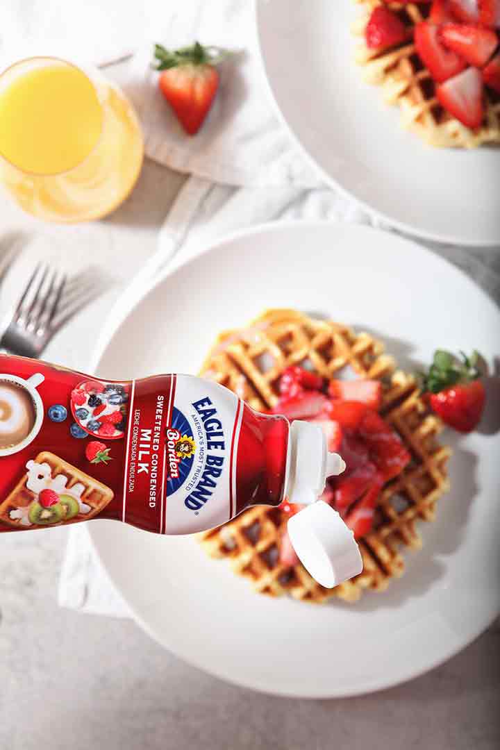 Eagle Brand sweetened condensed milk is drizzled onto waffles, from above