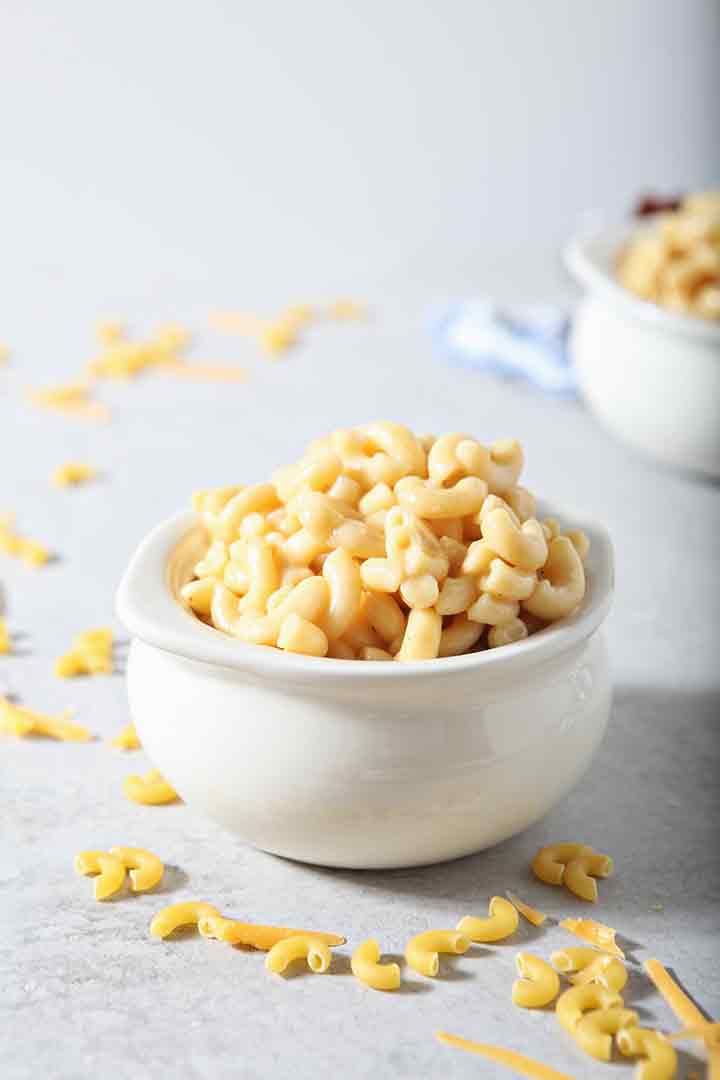 A bowl of Instant Pot Macaroni and Cheese is served on a grey background