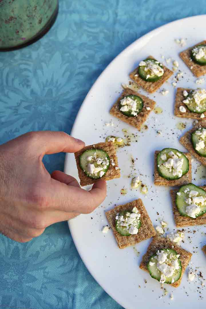 A man picks up a TRISCUIT Cucumber Bite off a white platter