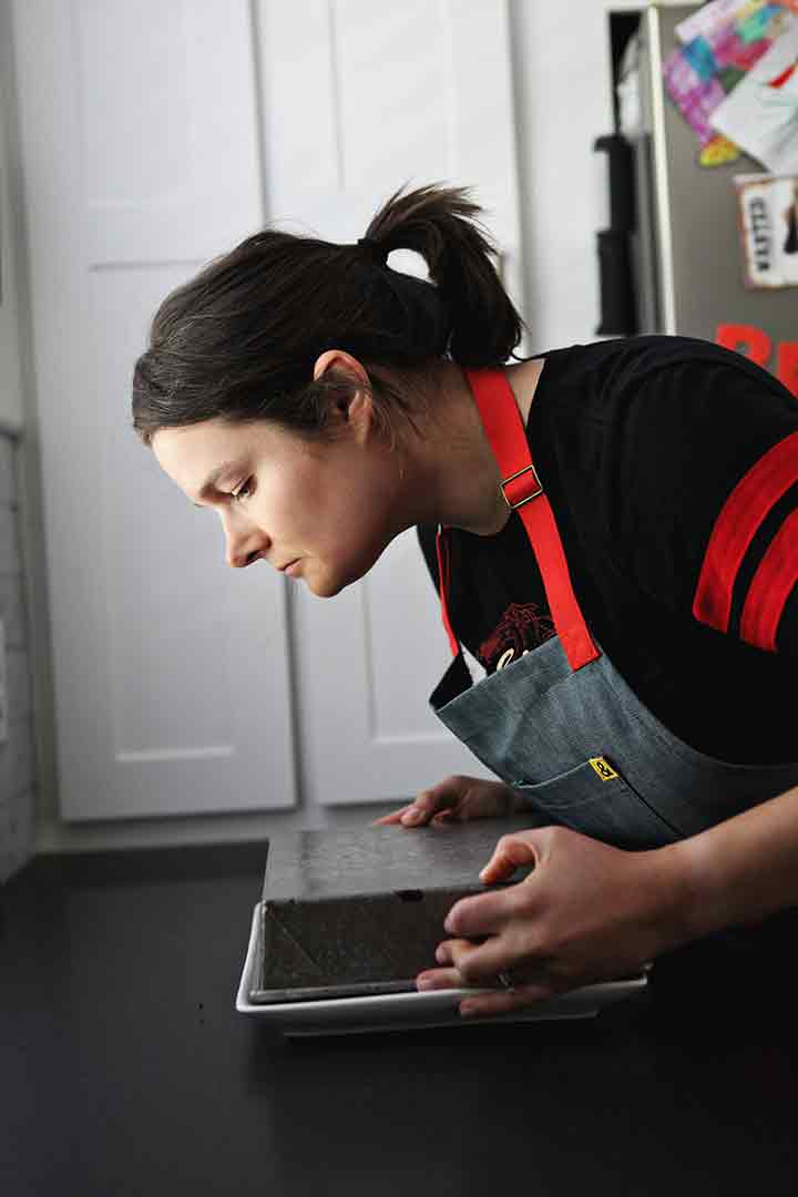 A woman flips a chocolate cake in its pan