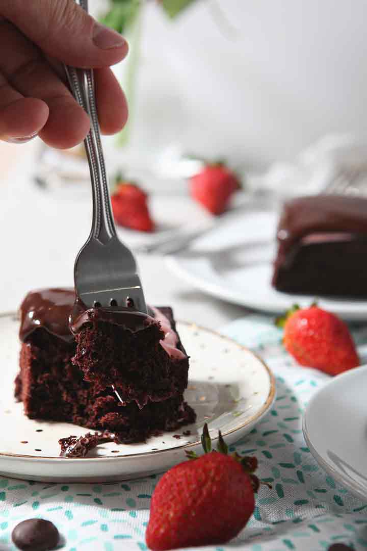 A fork cuts into a slice of Strawberry Chocolate Cake