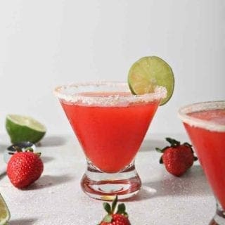 Close up of two Strawberry Margaritas, surrounded by fresh fruit