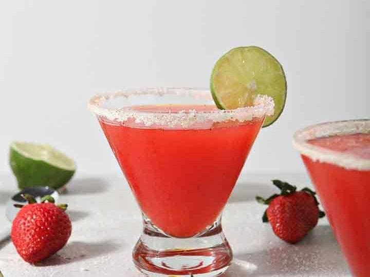 Close up of two Strawberry Margaritas, surrounded by fresh fruit