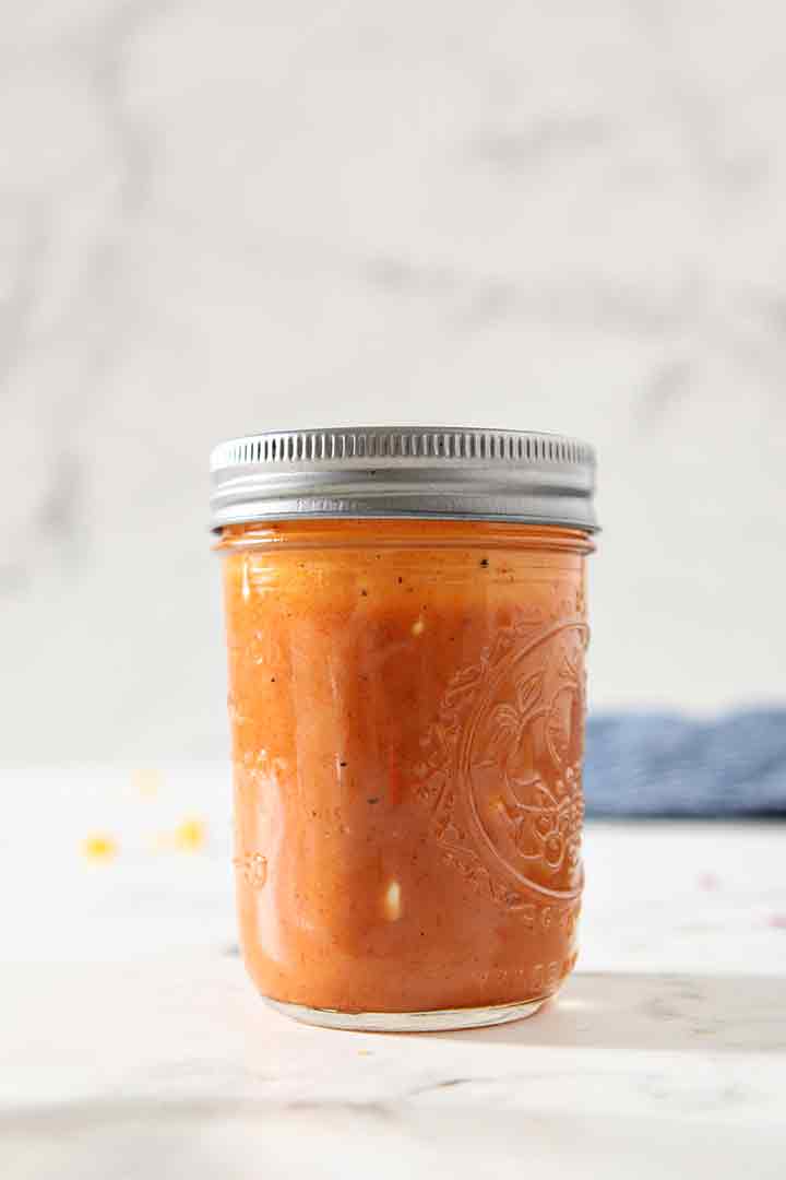 The salad dressing is shown in a mason jar on a white background