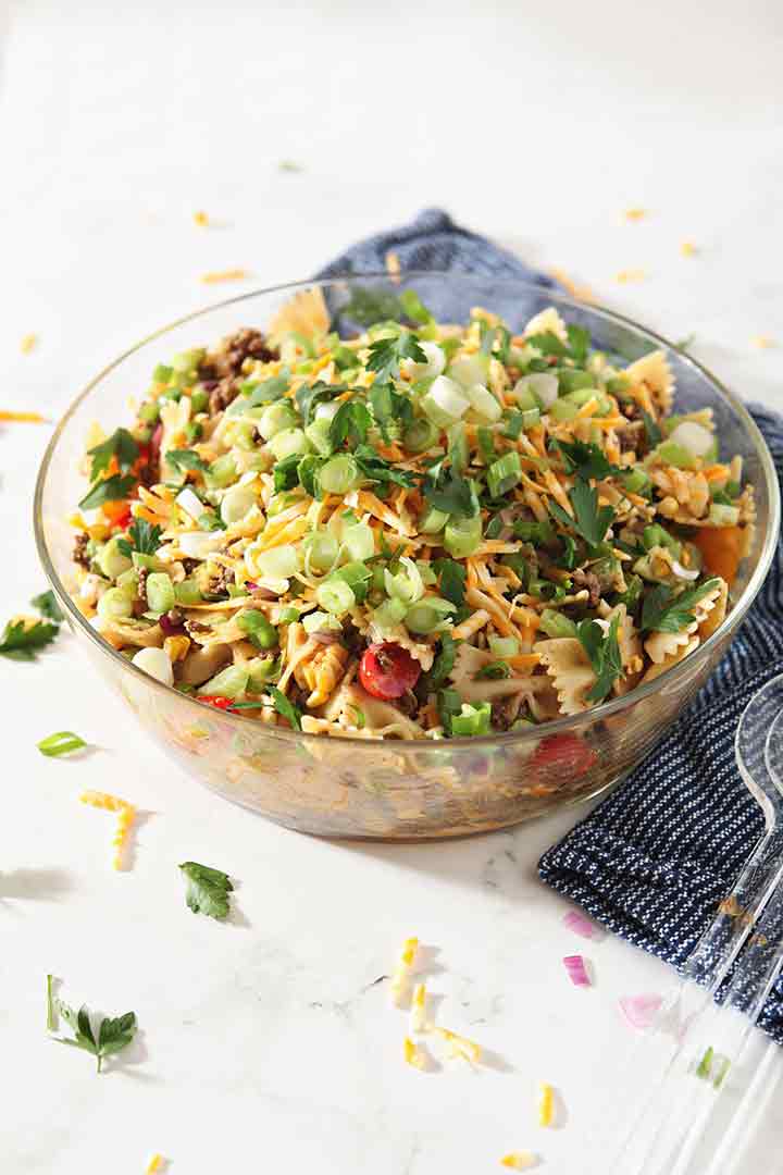 A giant bowl holding Beef Taco Pasta Salad sits on a table, ready for eating