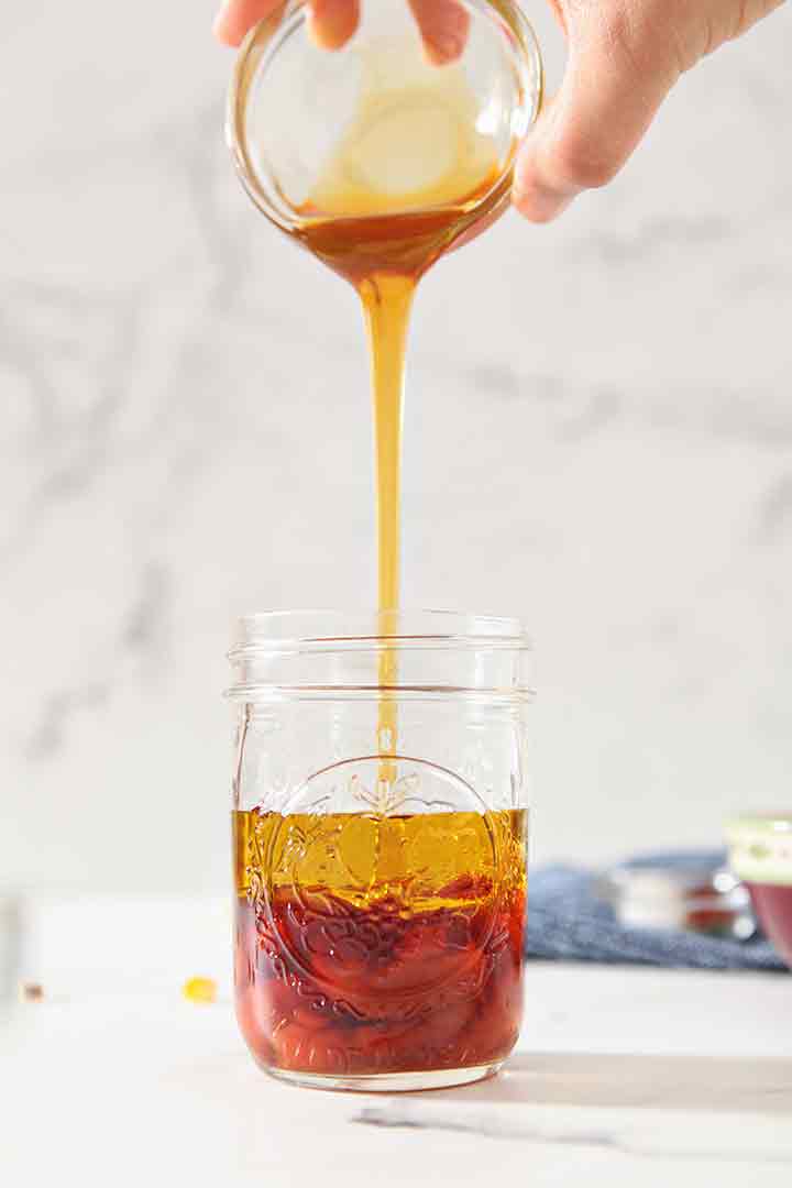 Honey is poured into a mason jar to make dressing