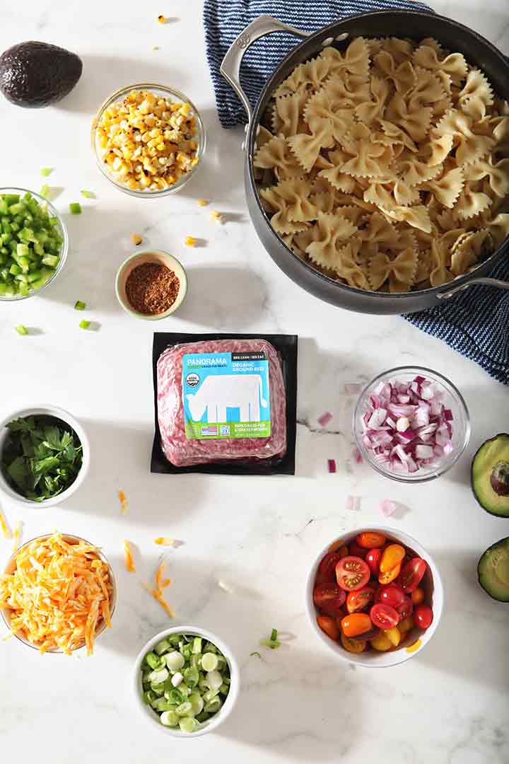 Ingredients for Beef Taco Pasta Salad are laid out on a white background