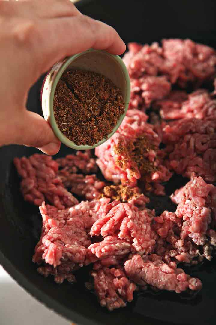 Ground beef is seasoned in a skillet