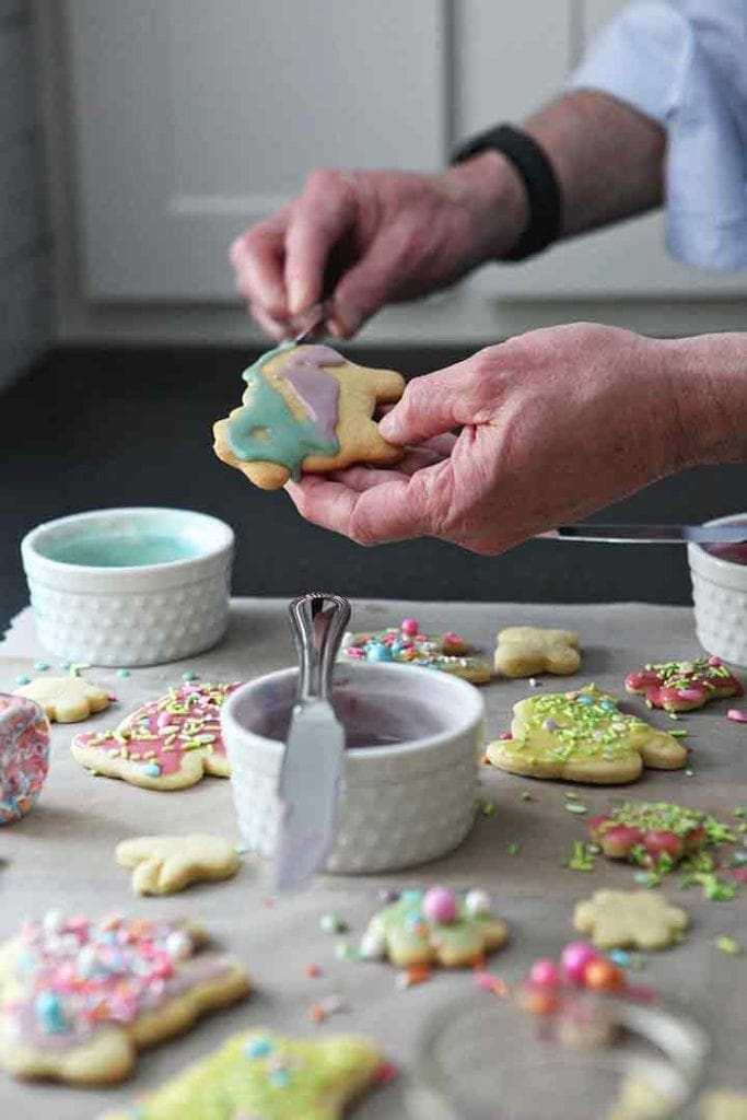 A man spreads Lemon Icing onto a sugar cookie