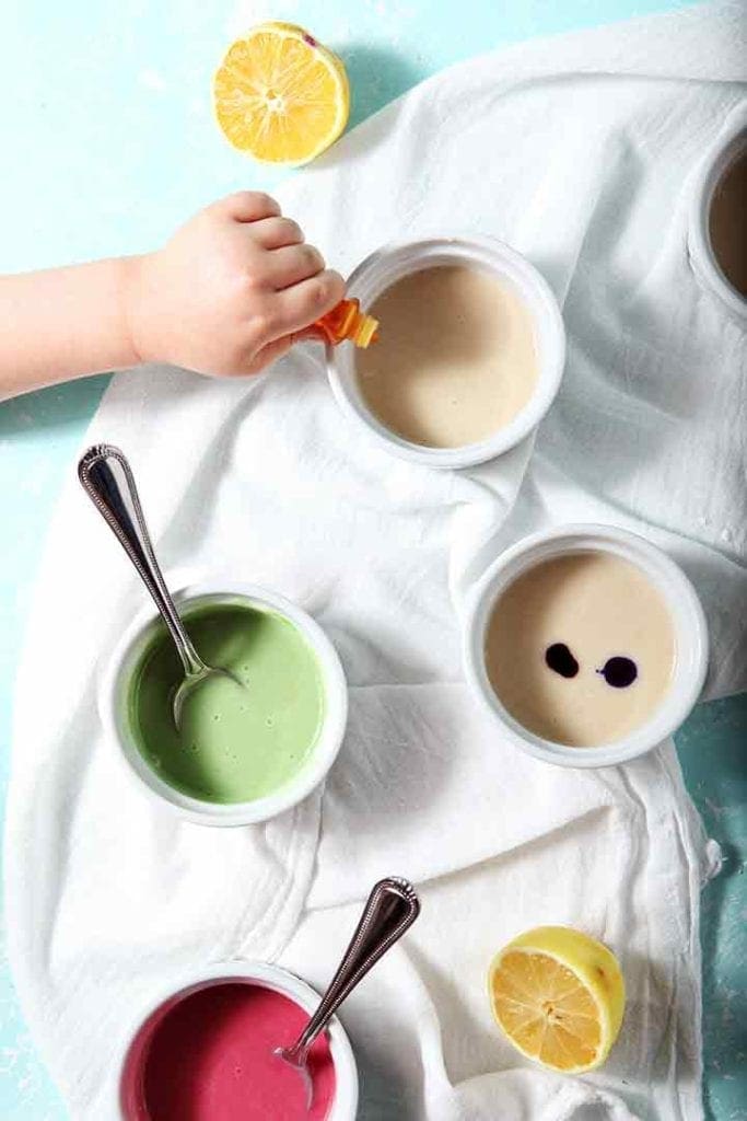 A girl drops food coloring into the individual icing containers