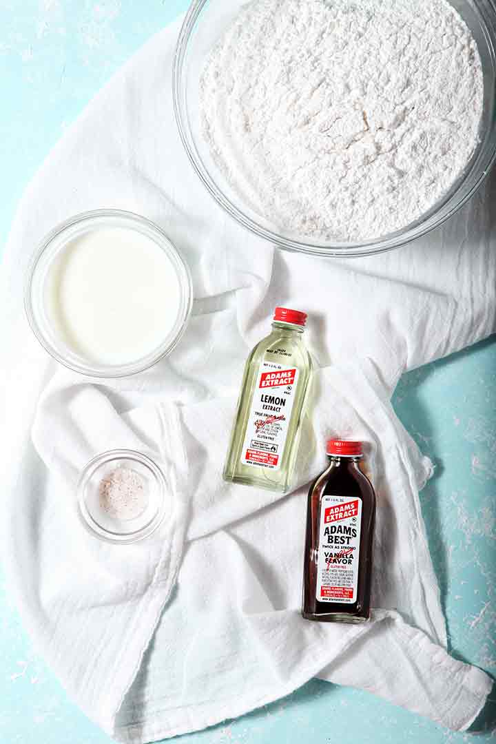 Powdered sugar, milk, salt, vanilla and lemon extracts are shown on a turquoise background