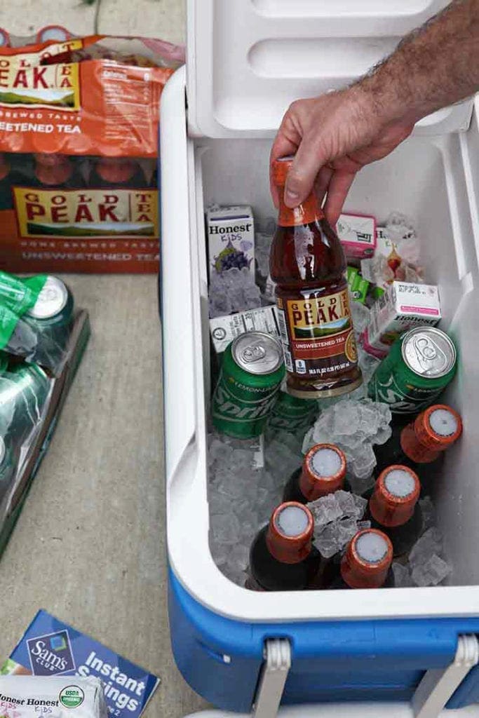 A man places drinks in a cooler to chill before an outdoor entertaining event