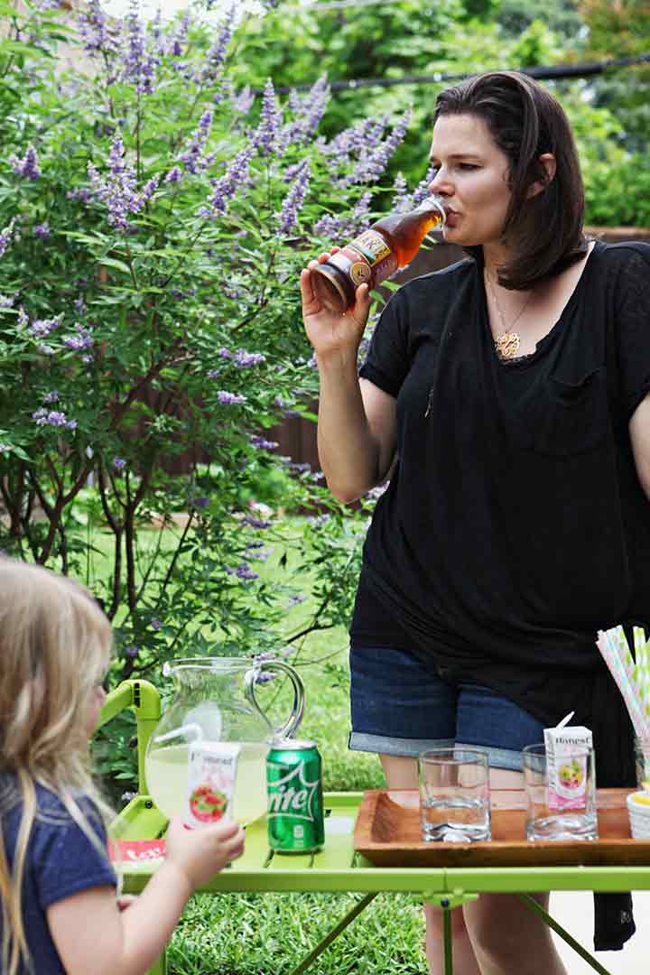 A woman and a child enjoy drinks at an homemade outdoor drink station