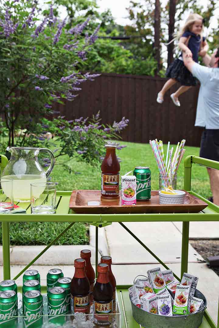 A man lifts a girl behind an outdoor bar cart