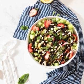 Overhead image of the final Strawberry Melon Salad in a white bowl with a blue napkin