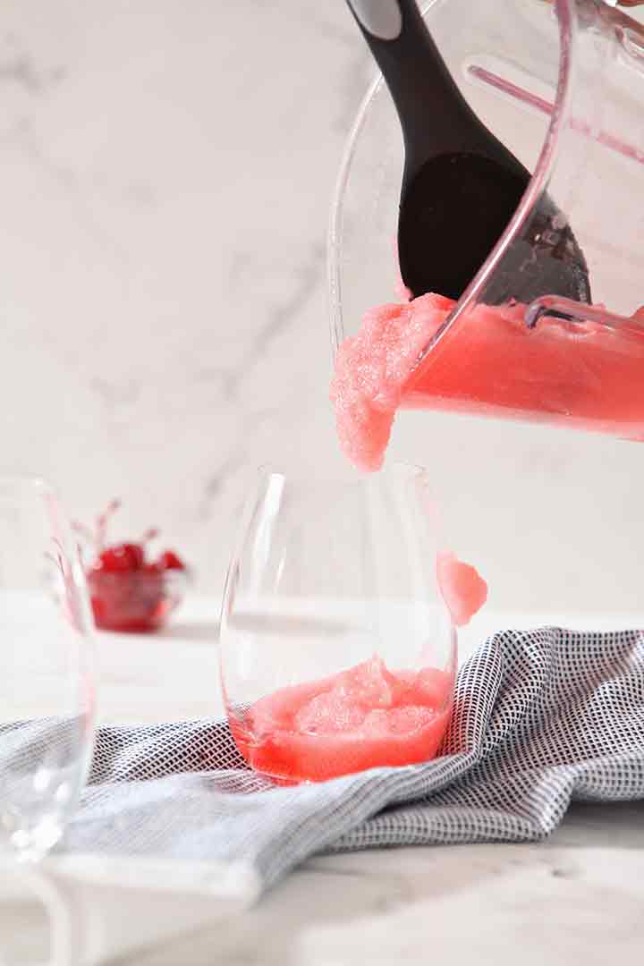 Cherry Bourbon Slush is poured into a cup from the blender