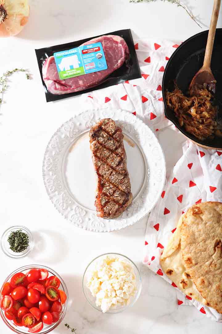 A grilled New York strip loin steak is shown with other grilled flatbread pizza ingredients