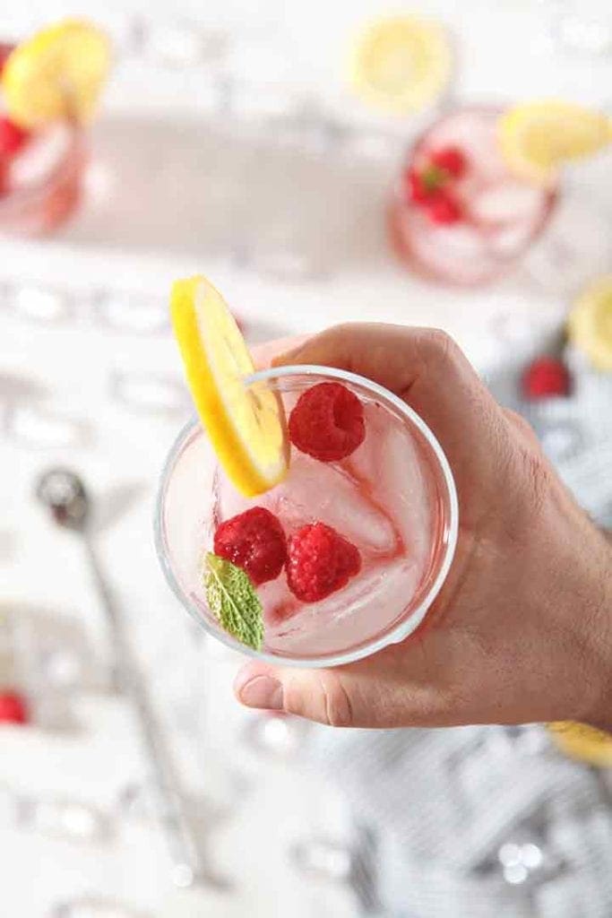 A man holds a glass of vodka raspberry lemonade