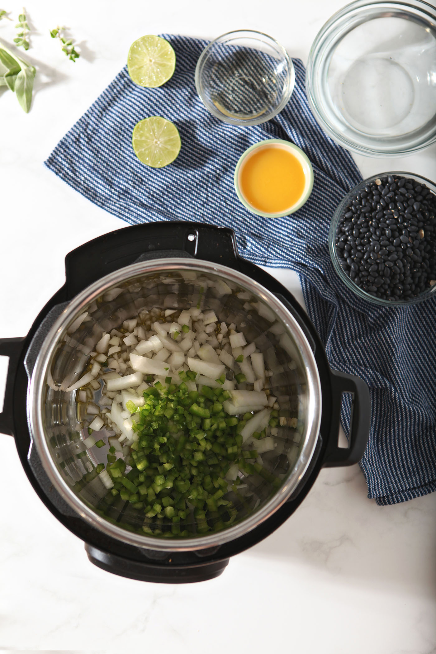 Aromatics in an Instant Pot, surrounded by bowls of other ingredients