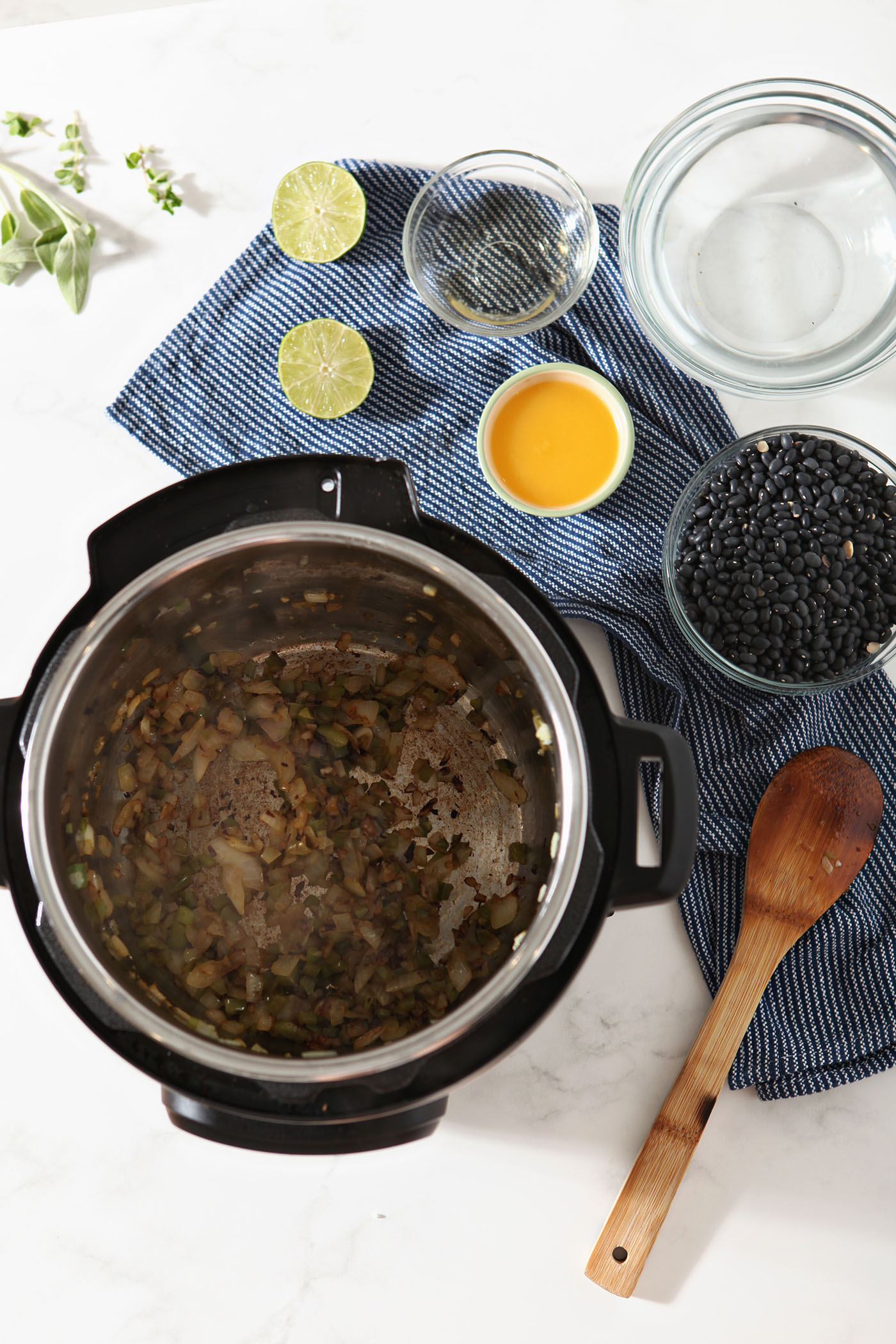 Cooked aromatics in the Instant Pot, surrounded by bowls of other ingredients.
