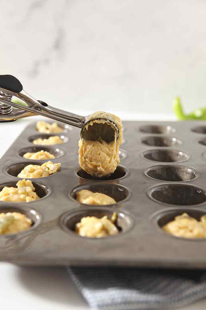 A cookie scoop is used to scoop the dough into the prepared mini muffin tin