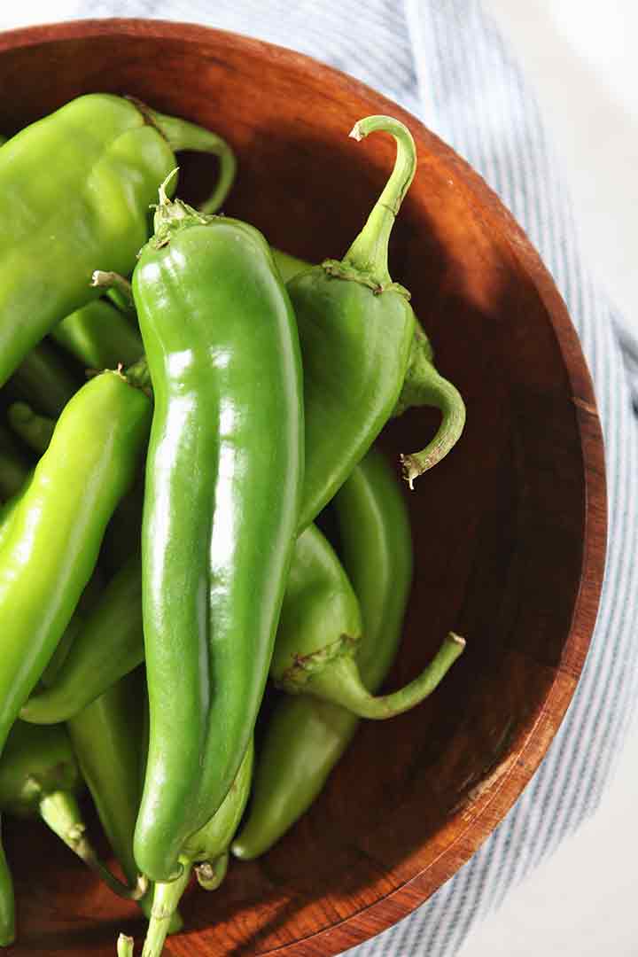 Green chiles are shown in a wooden bowl