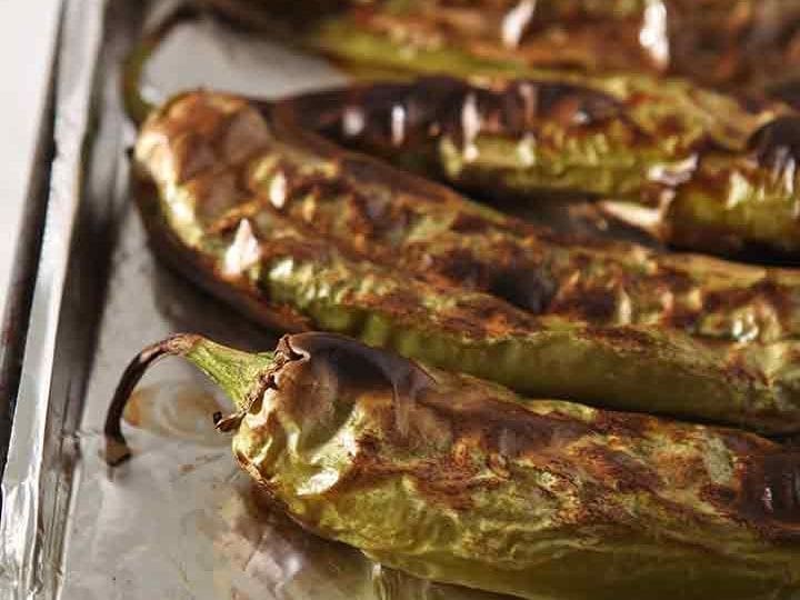 Roasted Hatch chiles line a baking dish, close up
