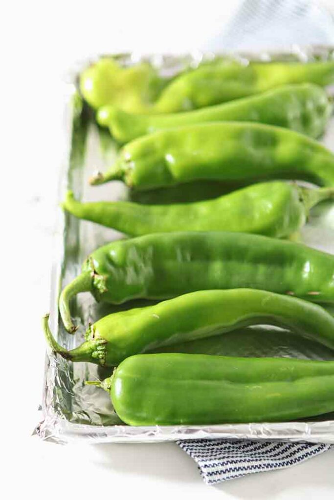 Hatch chile peppers are shown on a baking sheet, before roasting