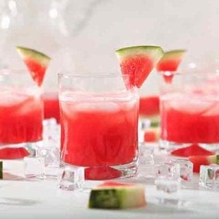 Several glasses of Watermelon Agua Fresca are garnished with watermelon wedges before drinking