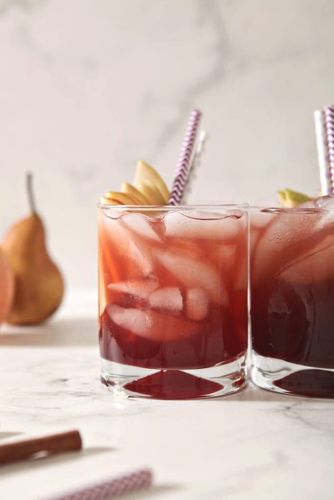 Glasses of Individual Apple Cider Punch are lined up in front of pears and apples