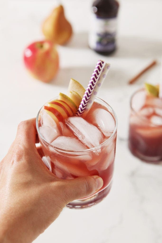 A woman grabs a glass of Individual Apple Cider Punch with Sambucus