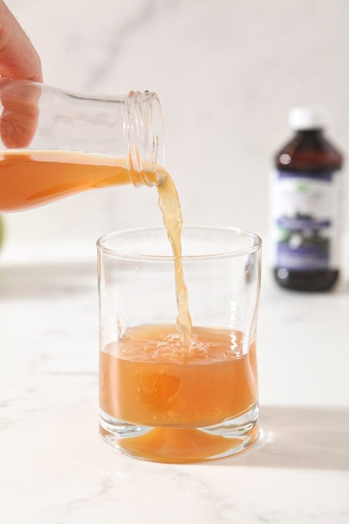 Apple cider is poured into a glass to make the mocktail