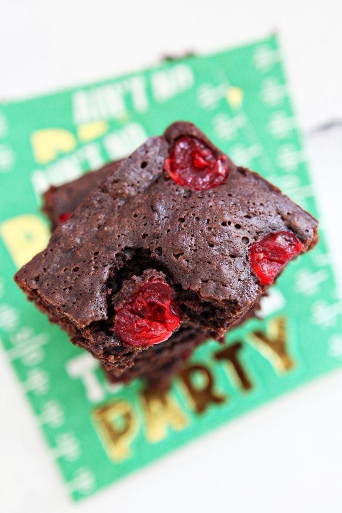 Overhead of brownies studded with cherries, from above, stacked on top of each other