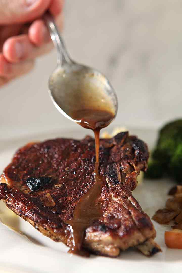 Pan juices are drizzled over a pork chop when serving