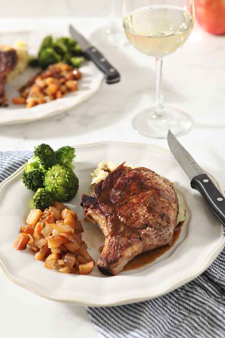 A final plate of Cinnamon Apple Pork Chop with steamed broccoli and mashed potatoes, served with wine