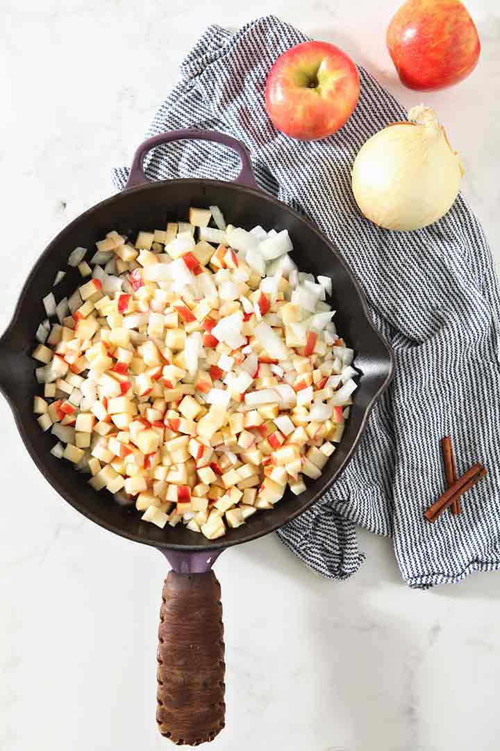 Apples and onions cook down in a cast iron skillet, from above