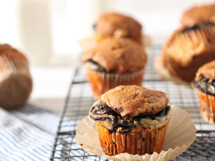 Easy Pumpkin Muffins with Cream Cheese and Nutella Swirl sit on a cooling rack with bottles of milk