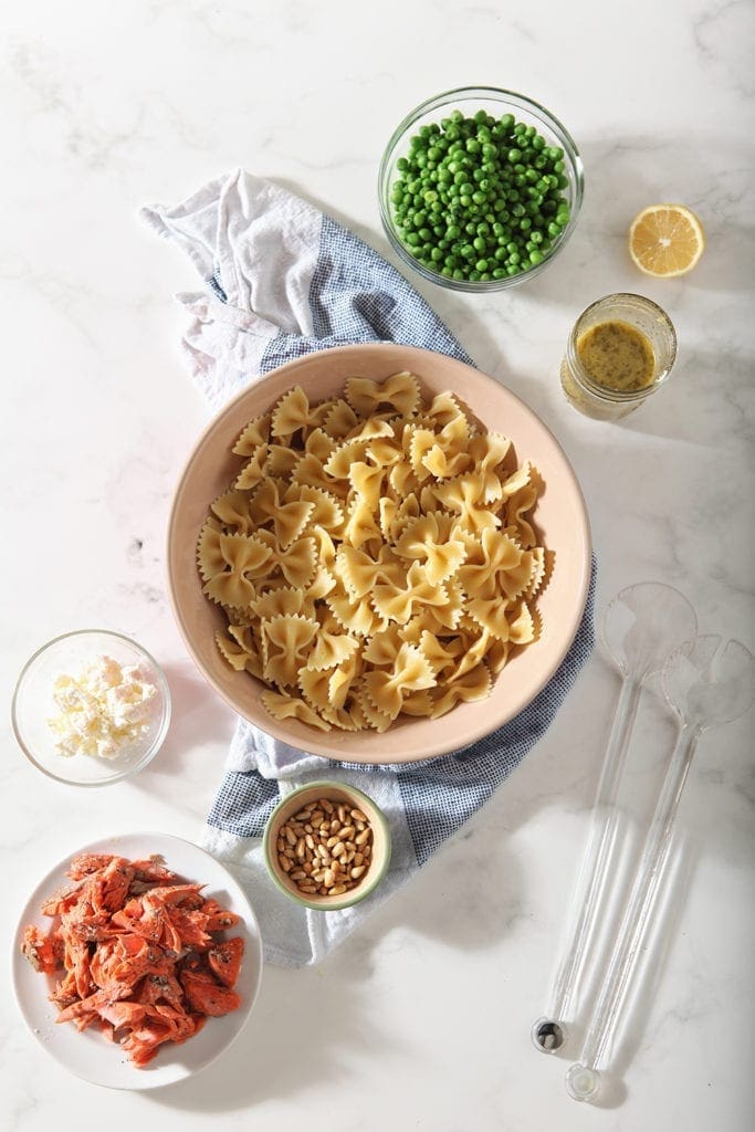 The ingredients for the pasta are laid out on a marble background in separate bowls before mixing