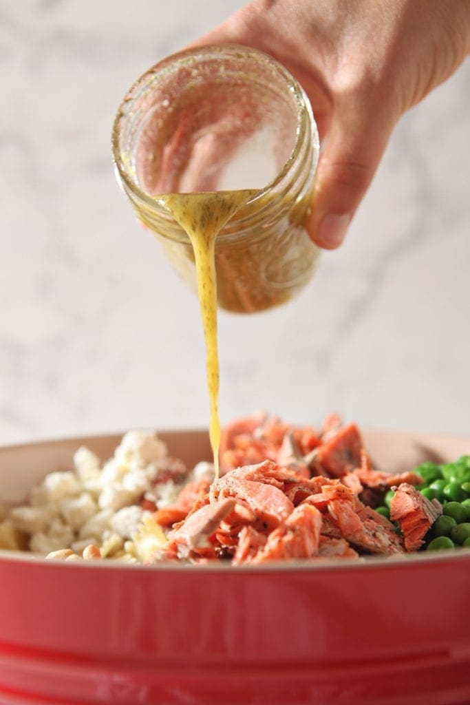 Lemon Vinaigrette is drizzled on top of the Salmon Pasta ingredients in a large bowl