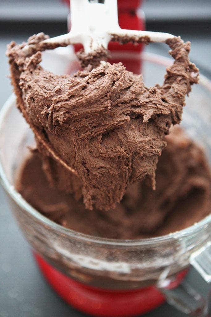 A stand mixer paddle holds chocolate batter, before the add-ins are stirred in