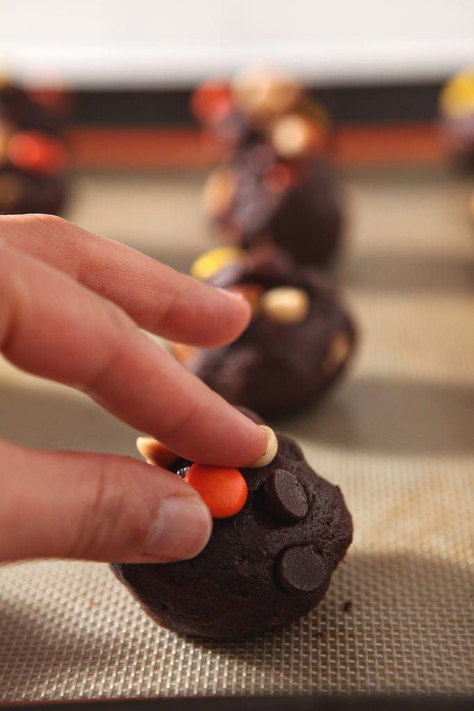 A woman presses a Reese's Pieces into a cookie before baking