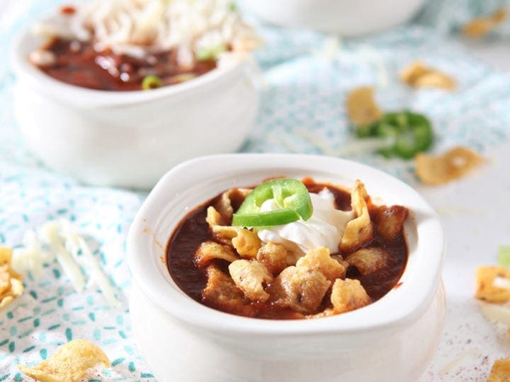 Three bowls of Homemade Texas Chili are topped with various ingredients